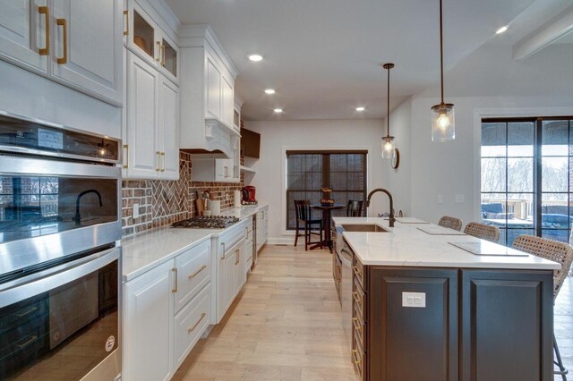 kitchen with a sink, tasteful backsplash, appliances with stainless steel finishes, and white cabinetry