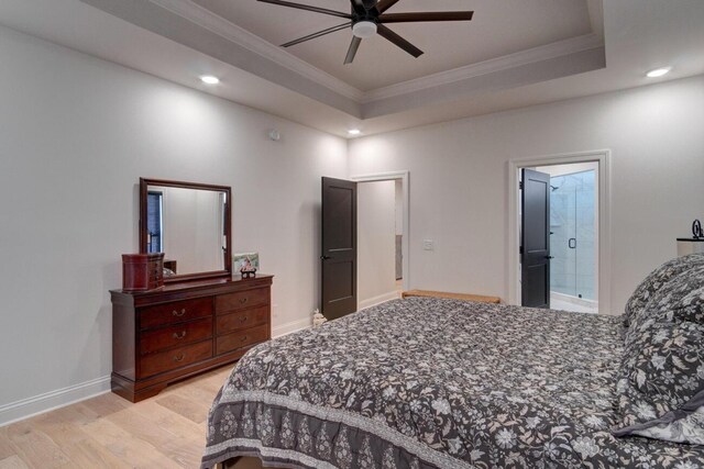 bedroom featuring a tray ceiling, crown molding, and light wood-style floors