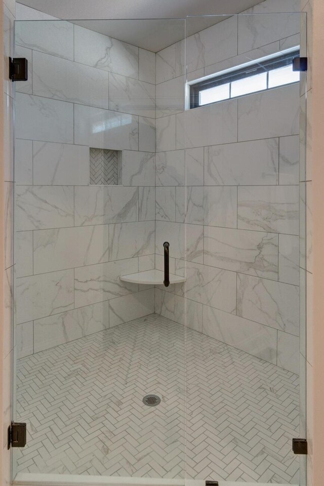 full bath with double vanity, a stall shower, marble finish floor, and a sink