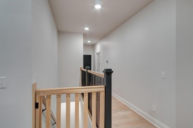 corridor with recessed lighting, wood finished floors, baseboards, and brick wall