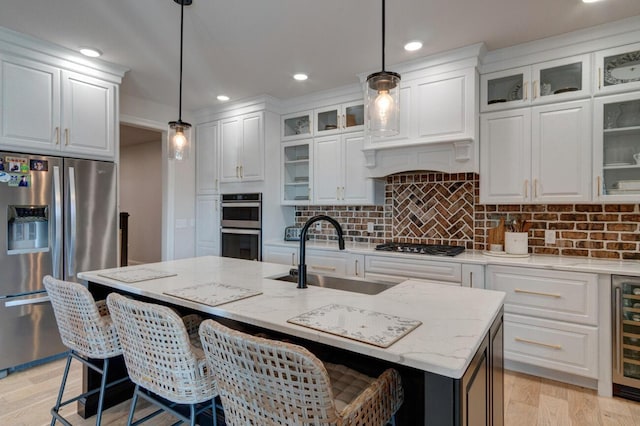 kitchen with a sink, decorative backsplash, stainless steel appliances, light wood-style floors, and white cabinetry