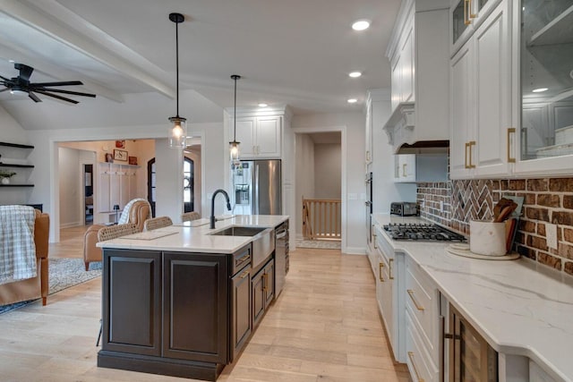 kitchen with stainless steel appliances, white cabinets, decorative backsplash, and light wood-style flooring