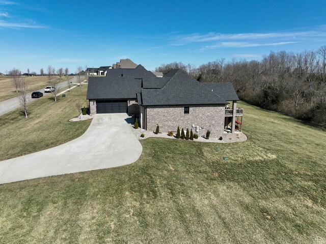 view of front of house with brick siding, concrete driveway, a front yard, roof with shingles, and an attached garage