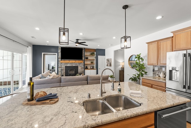 kitchen featuring light stone countertops, sink, pendant lighting, and appliances with stainless steel finishes