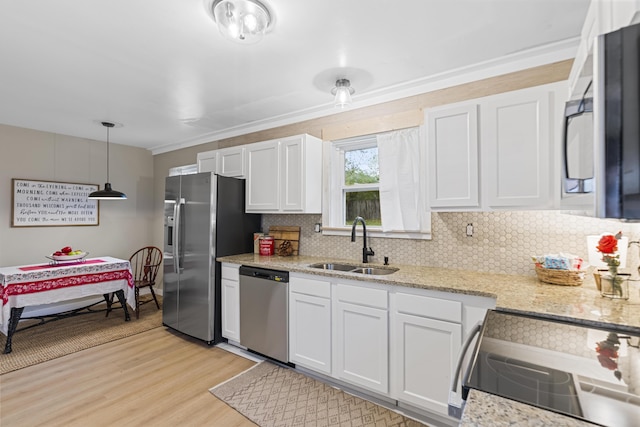 kitchen featuring sink, white cabinetry, stainless steel appliances, and hanging light fixtures