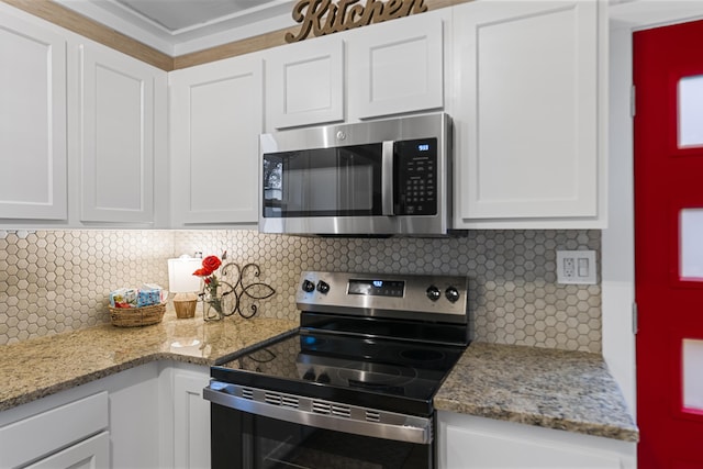 kitchen with light stone countertops, decorative backsplash, appliances with stainless steel finishes, and white cabinetry