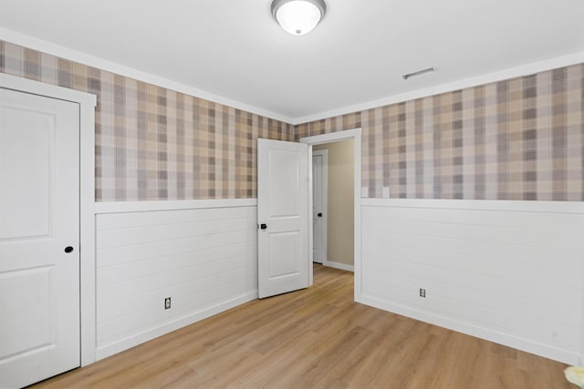 empty room with light hardwood / wood-style floors and ornamental molding