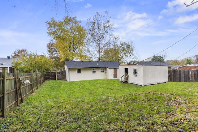 rear view of house featuring a yard and a storage shed