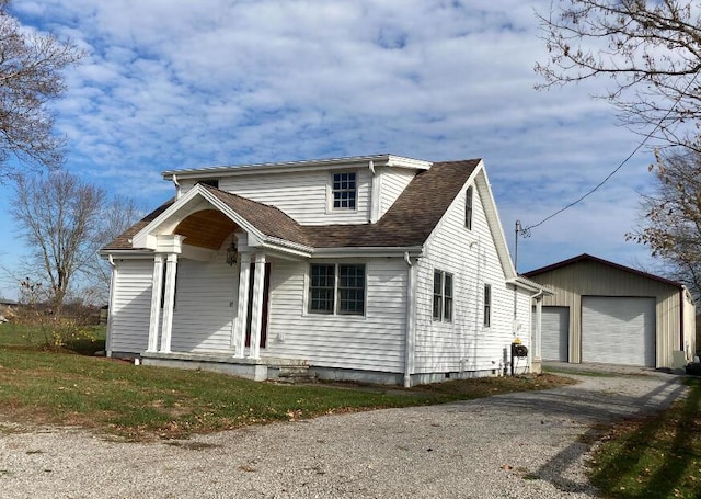 view of front of house featuring a shingled roof, a detached garage, and an outbuilding