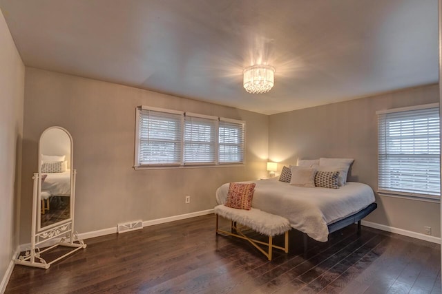 bedroom with dark hardwood / wood-style flooring and a chandelier