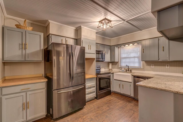 kitchen with gray cabinets, hardwood / wood-style floors, sink, crown molding, and stainless steel appliances