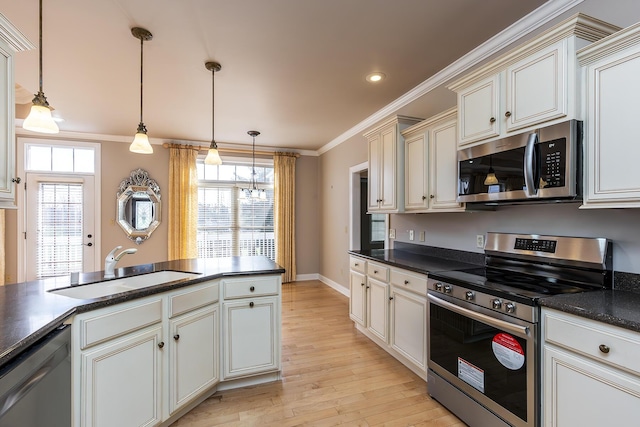 kitchen with pendant lighting, appliances with stainless steel finishes, a healthy amount of sunlight, sink, and cream cabinets