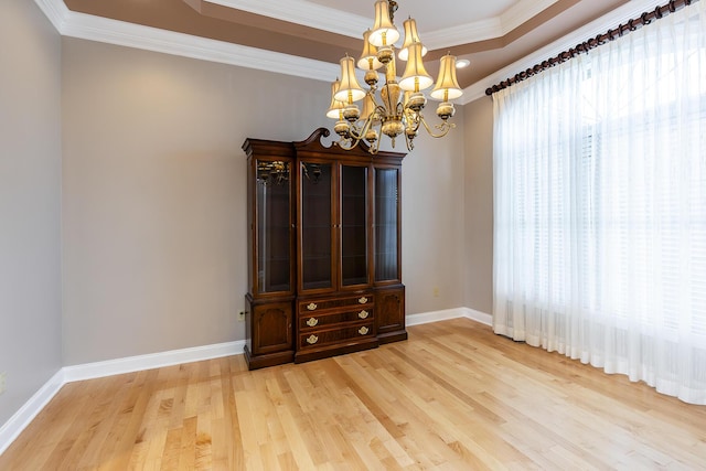 spare room featuring light wood-type flooring, a notable chandelier, and ornamental molding