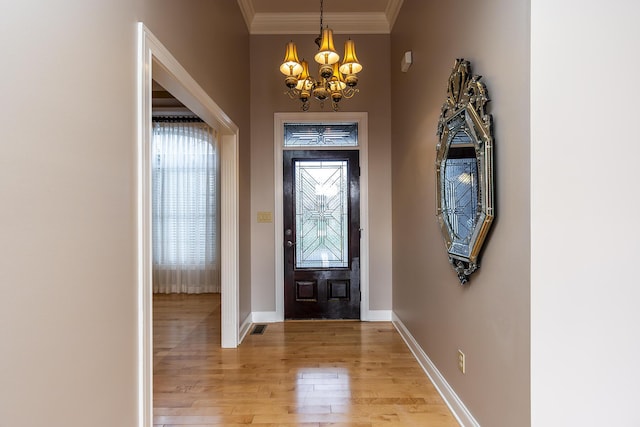 foyer entrance with crown molding, an inviting chandelier, and light hardwood / wood-style flooring