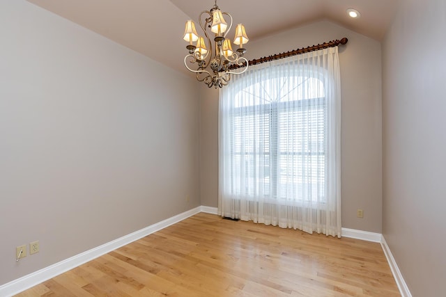 empty room featuring light wood-type flooring, vaulted ceiling, and a chandelier