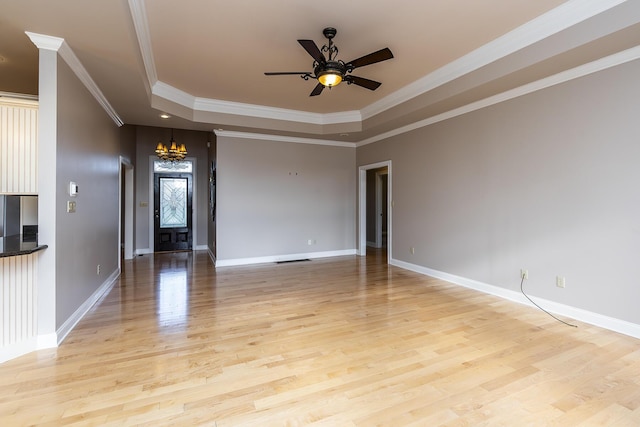 spare room with light hardwood / wood-style floors, ornamental molding, a raised ceiling, and ceiling fan with notable chandelier