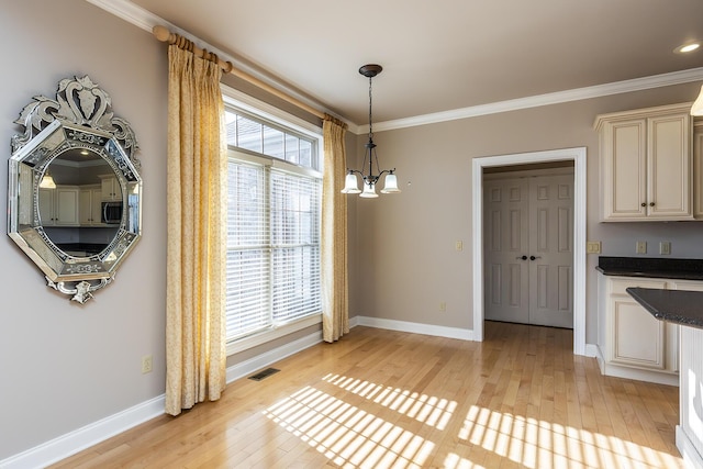 unfurnished dining area with ornamental molding, light hardwood / wood-style floors, and an inviting chandelier