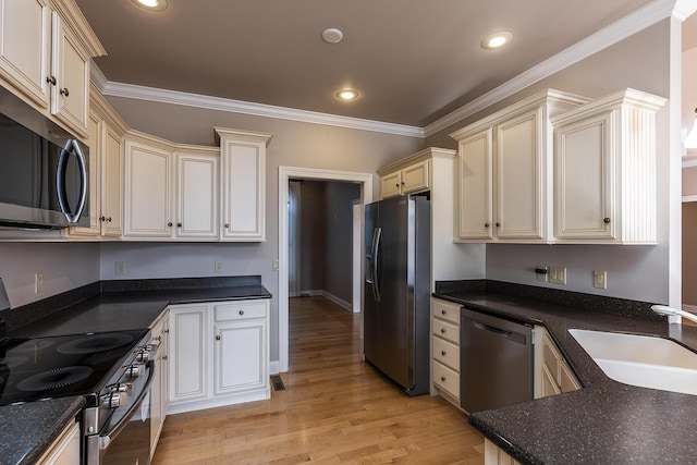 kitchen with sink, light wood-type flooring, cream cabinets, ornamental molding, and stainless steel appliances