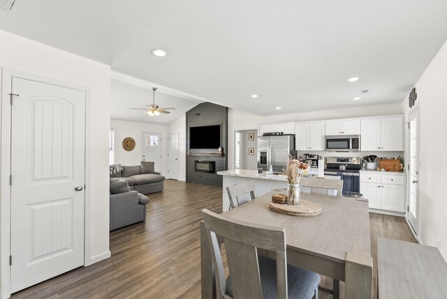 kitchen with appliances with stainless steel finishes, sink, white cabinets, an island with sink, and lofted ceiling