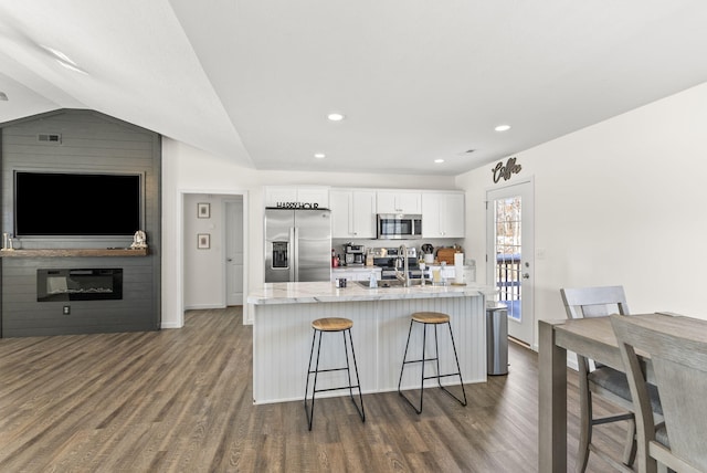 kitchen with appliances with stainless steel finishes, white cabinetry, sink, a breakfast bar, and dark hardwood / wood-style floors