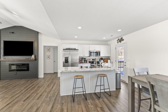 dining area with ceiling fan, dark wood-type flooring, a fireplace, and lofted ceiling