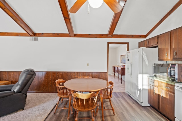 dining space with ceiling fan, lofted ceiling with beams, and light wood-type flooring