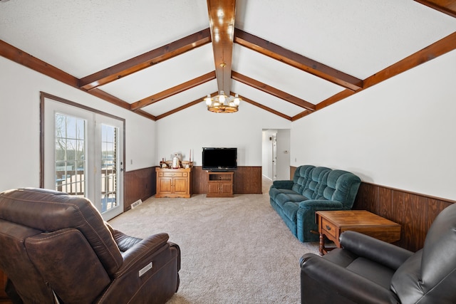 carpeted living room with a textured ceiling, wood walls, a chandelier, and vaulted ceiling