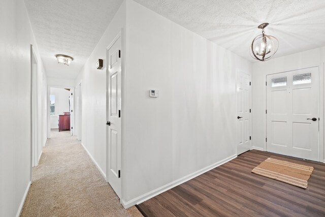 foyer entrance featuring carpet, an inviting chandelier, and a textured ceiling