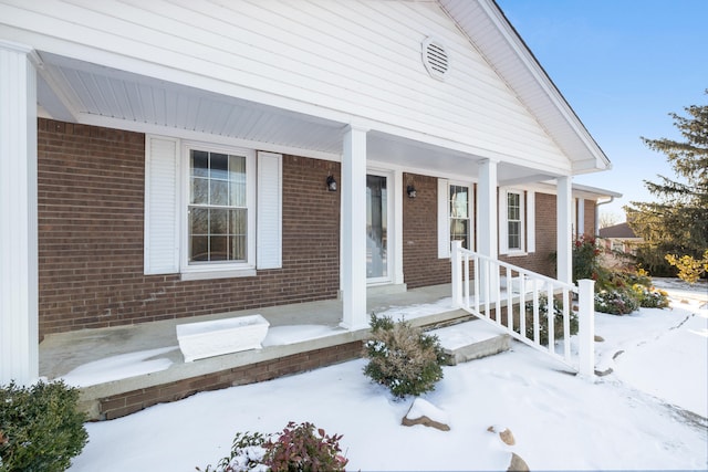 snow covered property entrance featuring covered porch