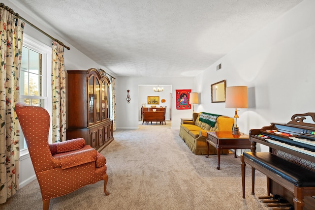 living area featuring light carpet, a chandelier, and a textured ceiling