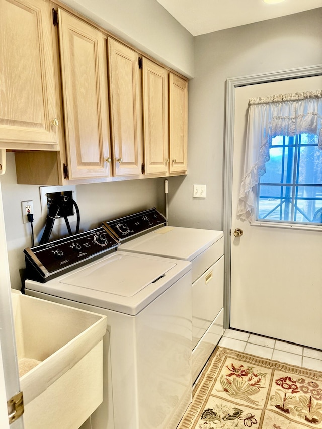 clothes washing area with washer and clothes dryer, sink, light tile patterned floors, and cabinets