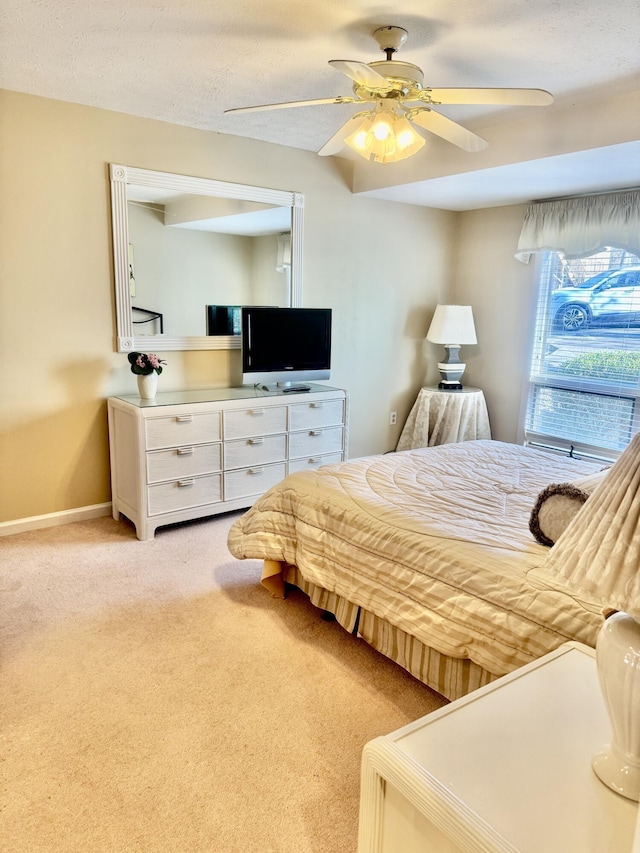 bedroom featuring ceiling fan, light colored carpet, and a textured ceiling