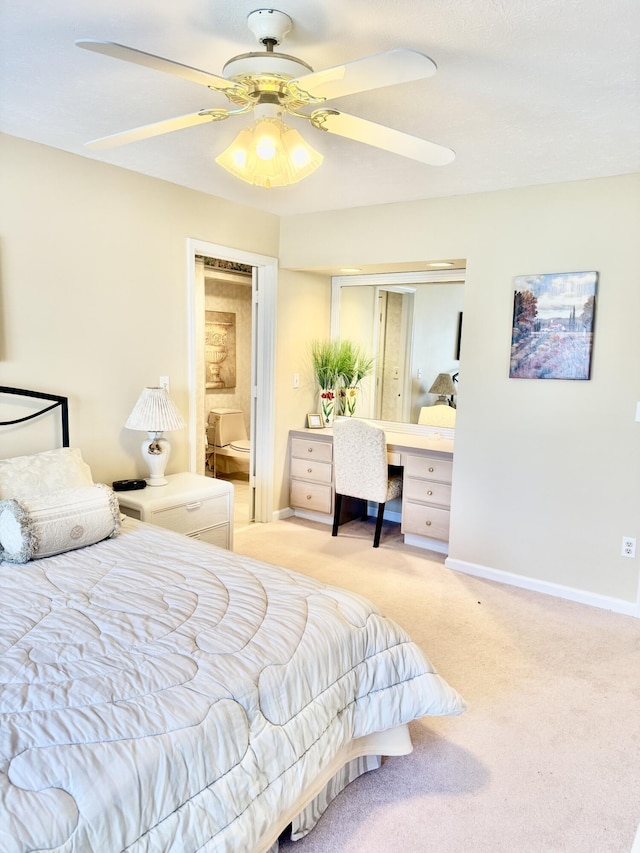 bedroom featuring connected bathroom, ceiling fan, built in desk, and light colored carpet