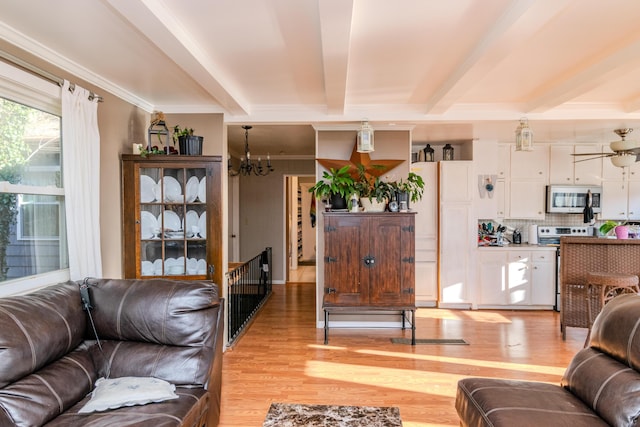 living room featuring beamed ceiling, ornamental molding, an inviting chandelier, and light hardwood / wood-style flooring