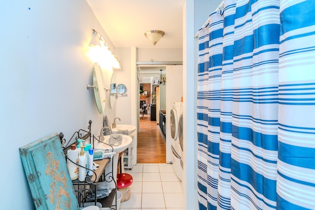 bathroom with sink, a notable chandelier, separate washer and dryer, curtained shower, and tile patterned floors