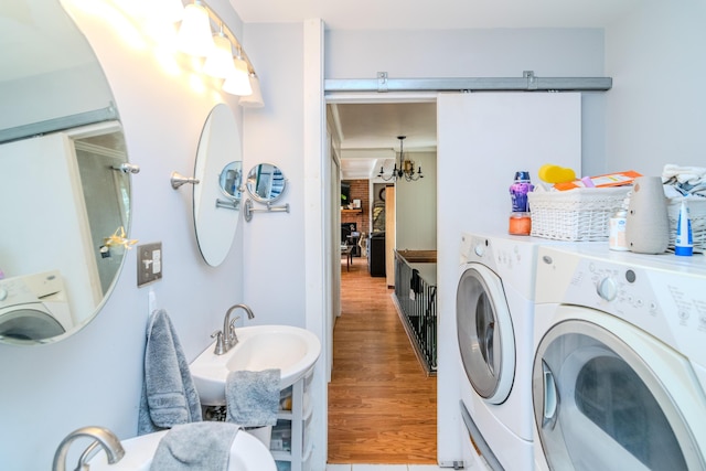 laundry room with washing machine and dryer, wood-type flooring, sink, and a chandelier