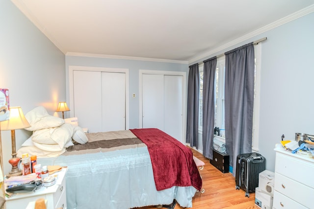 bedroom featuring crown molding, two closets, and light hardwood / wood-style floors