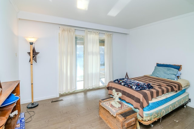 bedroom featuring hardwood / wood-style flooring, ornamental molding, multiple windows, and access to outside