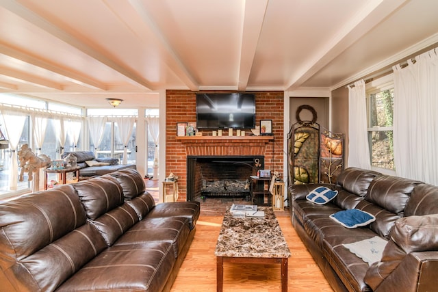 living room with a brick fireplace, beam ceiling, and light hardwood / wood-style flooring