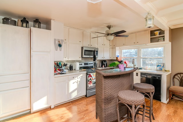 kitchen with light hardwood / wood-style flooring, ceiling fan, appliances with stainless steel finishes, white cabinetry, and decorative backsplash