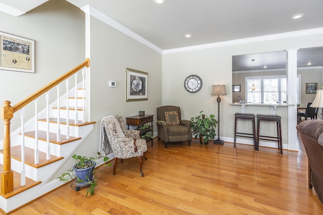 interior space with ornamental molding, decorative columns, and light wood-type flooring