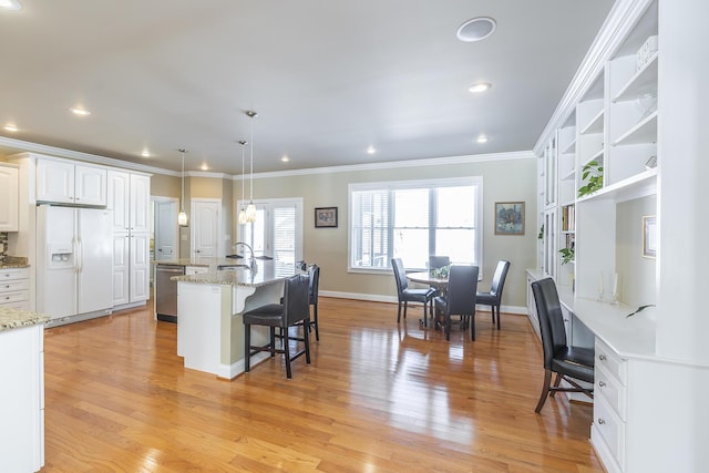 kitchen with pendant lighting, sink, dishwasher, white refrigerator with ice dispenser, and white cabinets