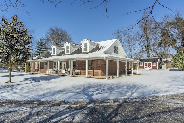 view of snow covered exterior with a shed and a porch