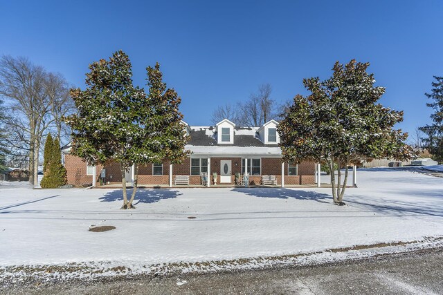 view of snow covered exterior with a porch and a storage unit