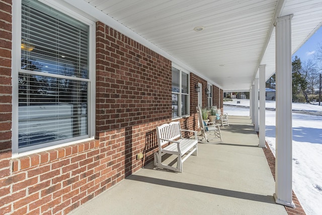 snow covered patio featuring a porch