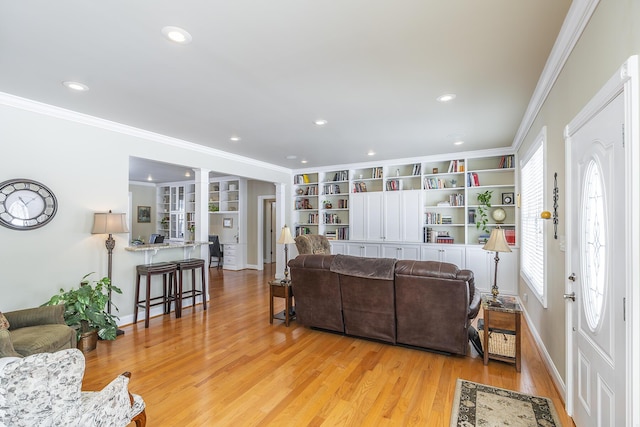 living room with crown molding, built in features, and light wood-type flooring