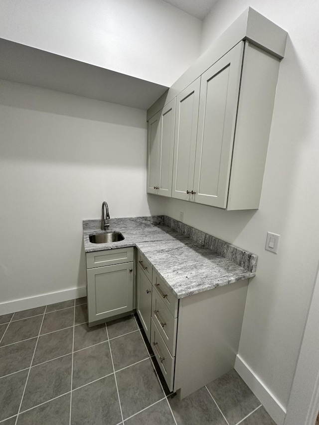 laundry area featuring dark tile patterned floors, sink, and cabinets