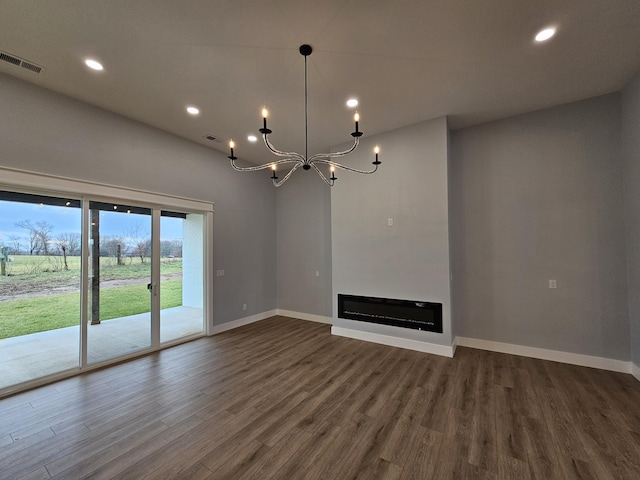 unfurnished living room with dark wood-type flooring and an inviting chandelier