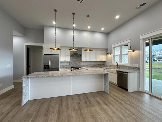 kitchen with appliances with stainless steel finishes, white cabinetry, and a center island