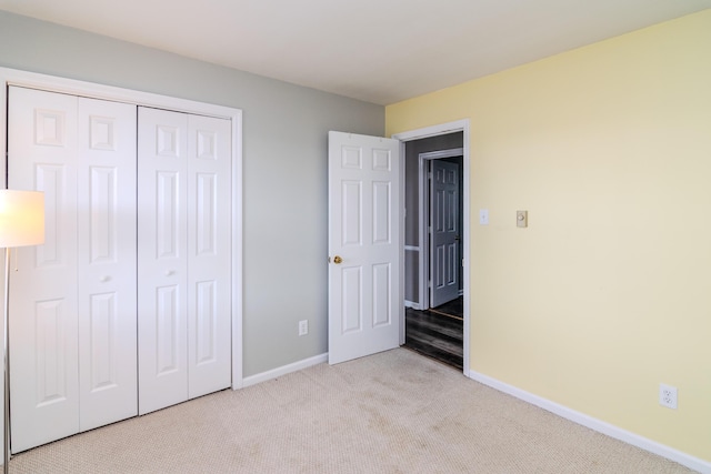 unfurnished bedroom with light colored carpet and a closet